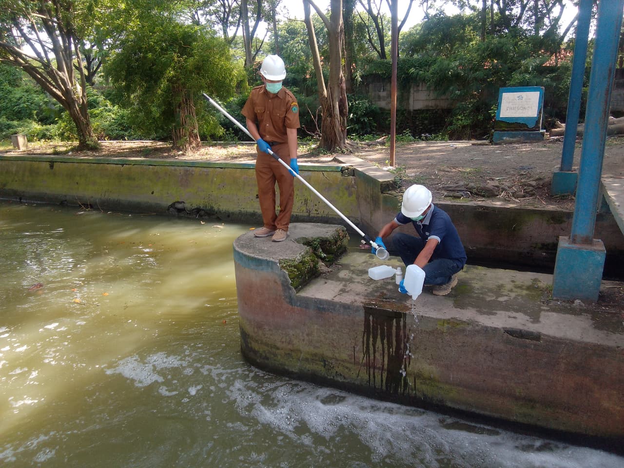 LABORATORIUM: Petugas DLHK Sidoarjo mengambil sampel air di Sungai Dam Bono, Desa Sedati Gede, Kecamatan Sedati. (DIKY SANSIRI/RADAR SIDOARJO)
