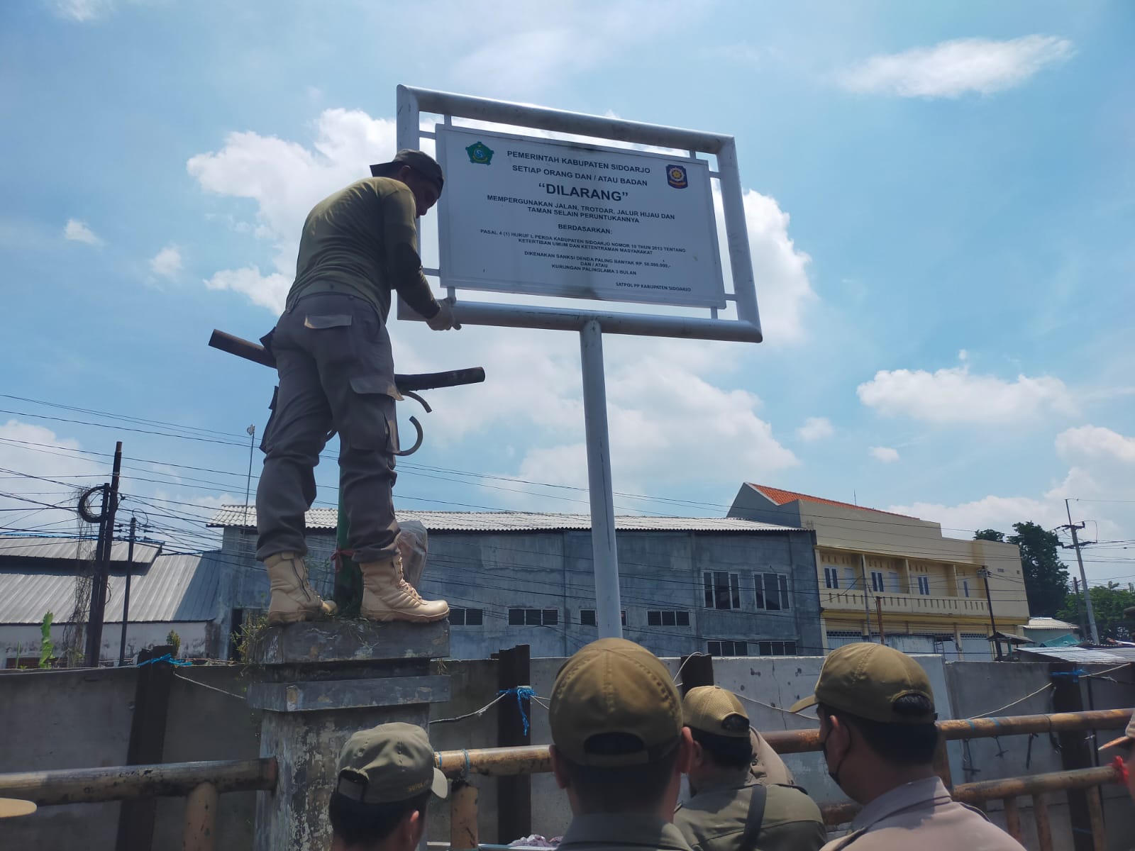 PENCEGAHAN: Petugas Satpol PP Sidoarjo memasang rambu larangan berjualan di fasilitas umum kawasan Waru, Sidoarjo.