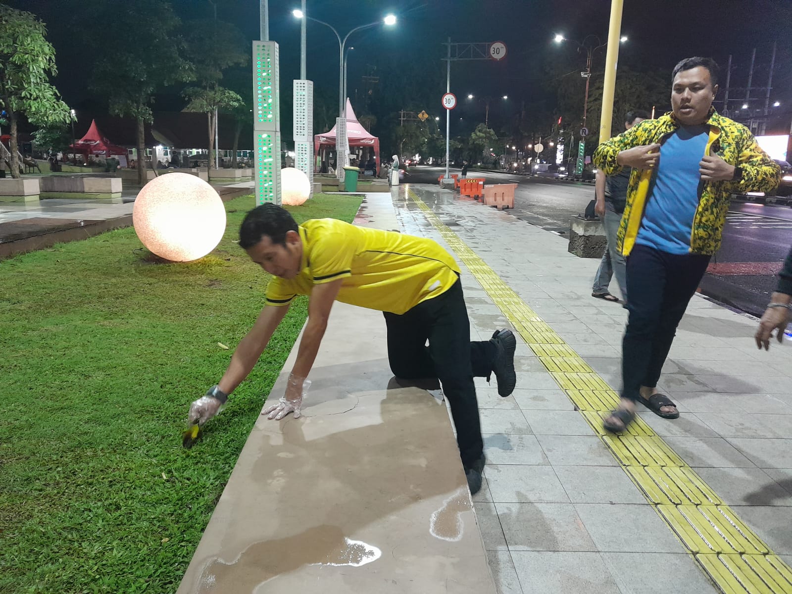 PEDULI: Ketua DPD Partai Golkar Sidoarjo Adam Rusydi (kiri) memungut sampah di Alun-alun Sidoarjo, Rabu (4/2/2026) malam.