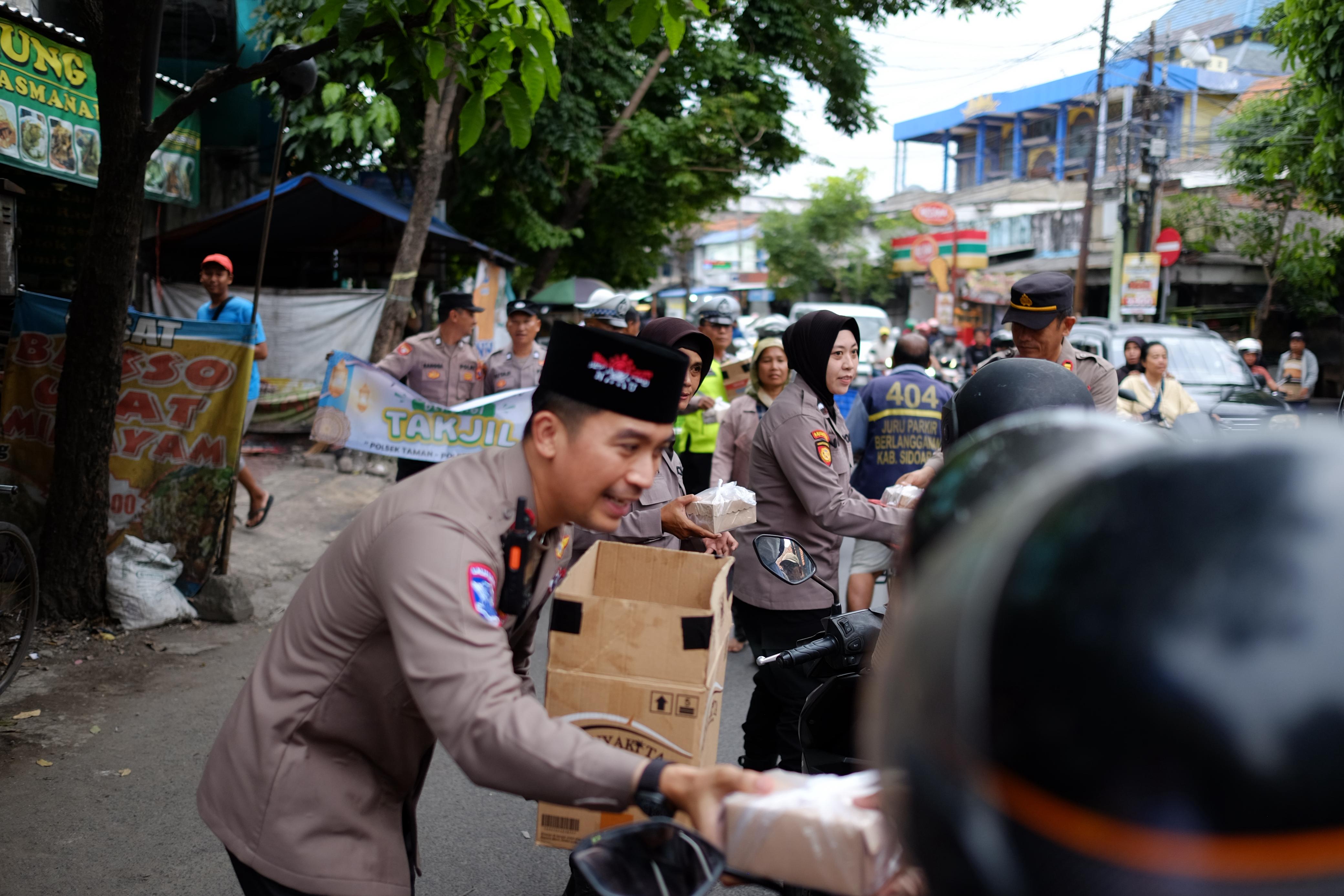 ST PEDULI: Kapolsek Taman Kompol Kanisius Franata bersama jajaran membagikan takjil kepada para pengguna jalan yang melintas di Jalan Raya Wonocolo, Sidoarjo.