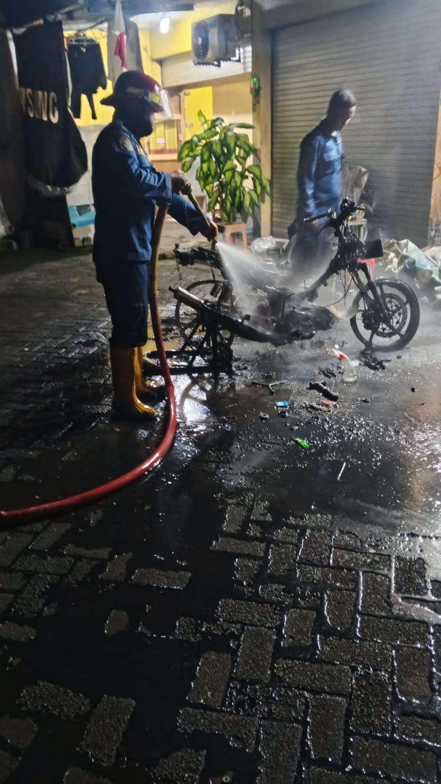 PEMBASAHAN: Petugas Damkar memadamkan api yang menghanguskan motor.
