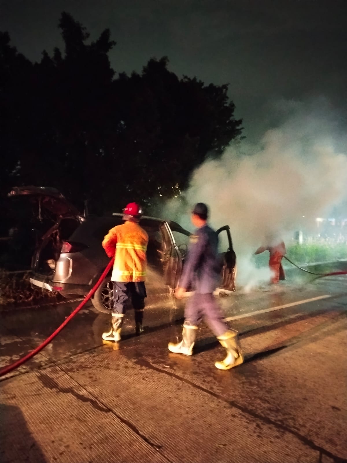 HANGUS: Petugas pemadam kebakaran memadamkan api yang membakar mobil di Krian, Sidoarjo.