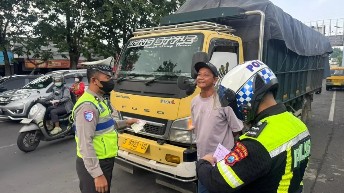 TEGAS: Personel Satlantas Polresta Sidoarjo memberikan teguran kepada sopir truk yang melanggar pembatasan operasional.