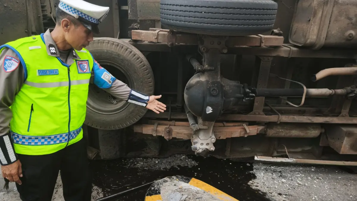 PATAH AS: Petugas kepolisian memeriksa kendaraan truk yang terguling sebelum gate Tol Waru Utama.&nbsp;