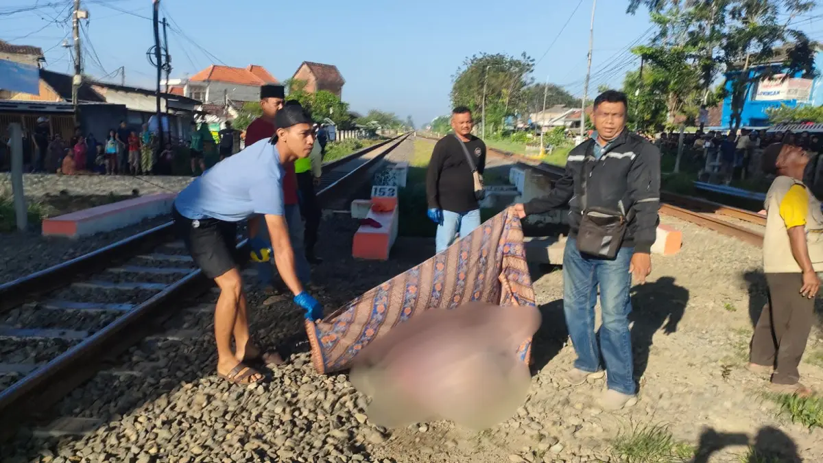 NAHAS: Petugas berusaha mengevakuasi jenazah RS, 71, yang tersambar kereta api di Krian, Sidoarjo.&nbsp;