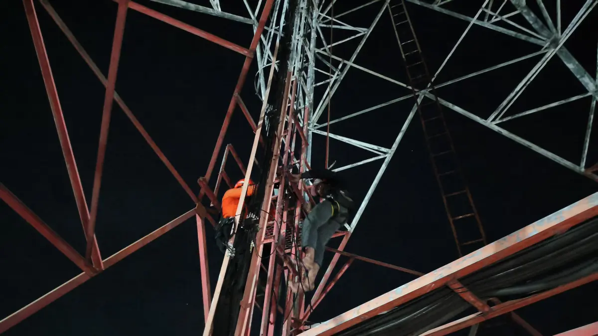 NAIK TOWER: Tim SAR gabungan mengevakuasi Andika Resta, 26, yang nekat memanjat menara telekomunikasi di Desa Kwangsan, Sedati.&nbsp;