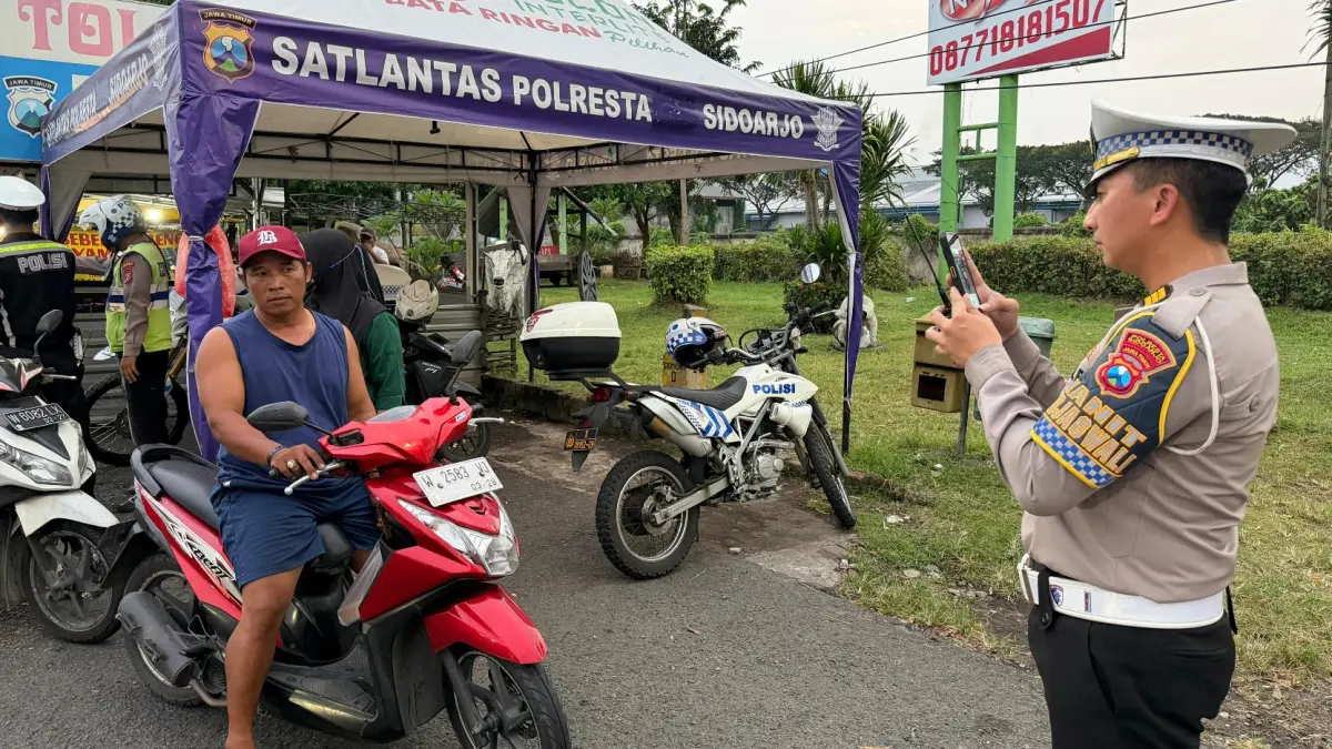DITILANG: Personel Satlantas Polresta Sidoarjo saat menindak pelanggar lalu lintas menggunakan sistem Electronic Traffic Law Enforcement (ETLE) Handheld di Sidoarjo.&nbsp;