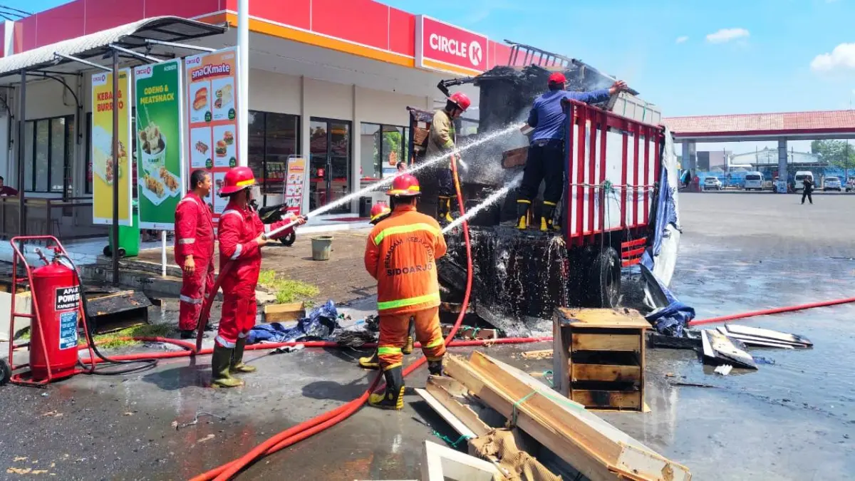 BERJIBAKU: Petugas pemadam kebakaran berupaya memadamkan api yang membakar sebuah truk di kawasan SPBU Jalan Raya Juanda, Sedati.