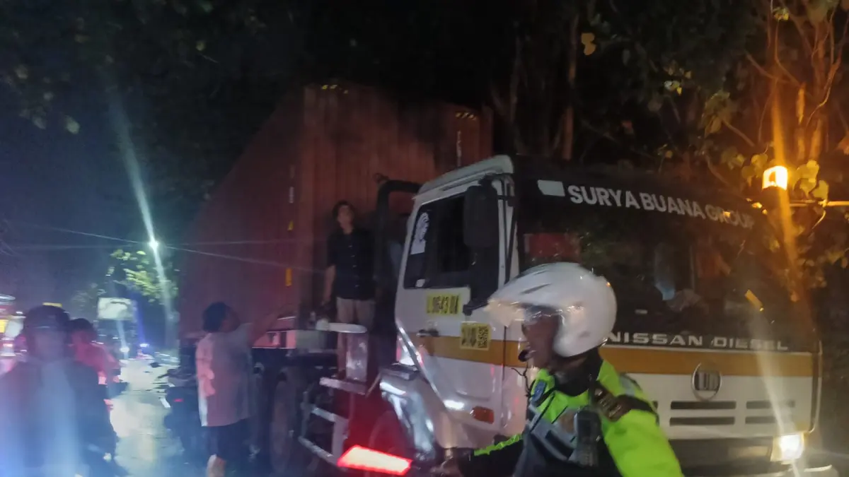 EVAKUASI: Petugas bersama warga mengevakuasi pohon tumbang yang menimpa truk kontainer di kawasan Krian, Sidoarjo.