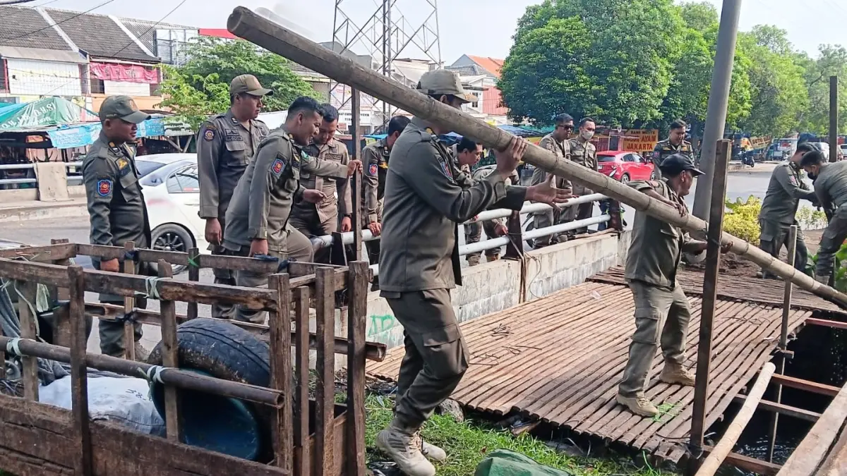 PERSUASIF: Petugas Satpol PP membongkar lapak yang digunakan untuk berjualan hewan kurban. (SURYANTO/RADAR SIDOARJO)