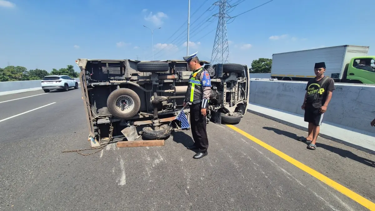 KECELAKAAN: Petugas kepolisian melakukan pemeriksaan terhadap mobil boks bermuatan galon air mineral yang terguling di KM 767 Tol Surabaya-Gempol.