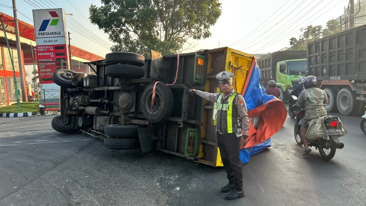 KECELAKAAN: Personel Polsek Krian saat memeriksa truk yang terguling di Tropodo, Krian, Sidoarjo.
