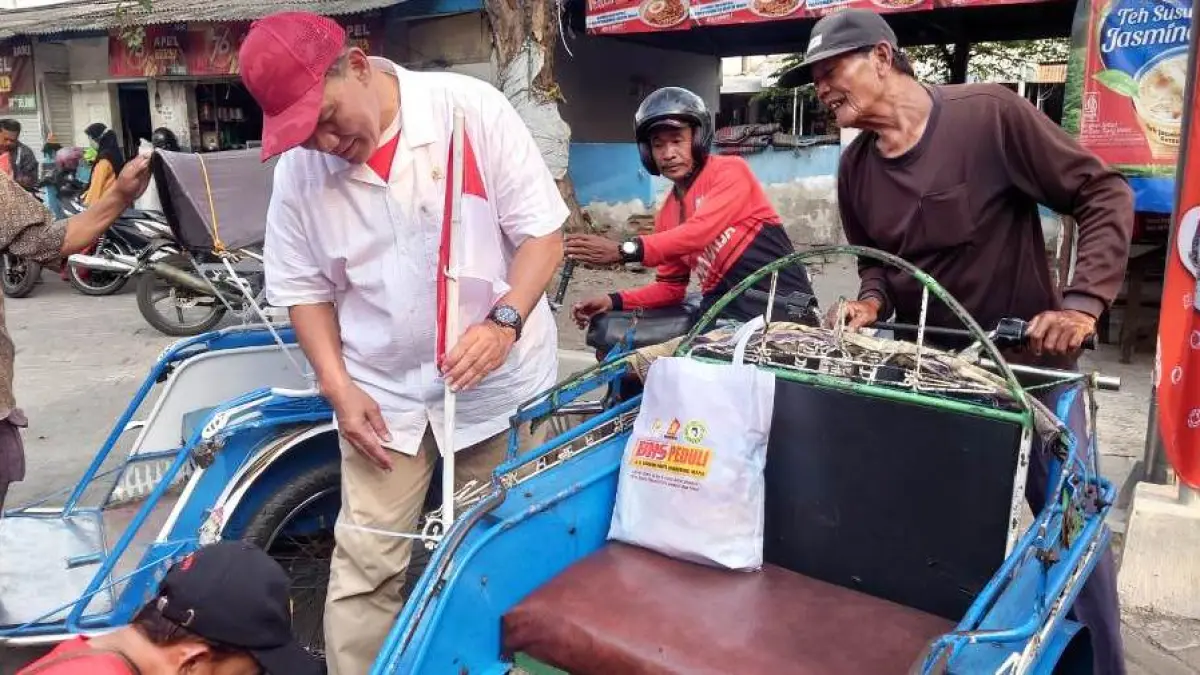 SENANG: Ketua Kelompok Fraksi (Kapoksi) Komisi VII DPR RI Ir. H. Bambang haryo Soekartono, M.I.Pol memasang bendera merah putih ke becak.
