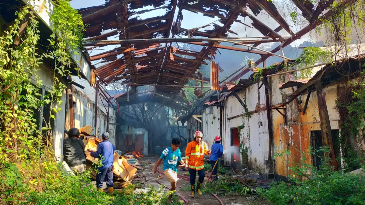 HANGUS: Petugas pemadam kebakaran dan warga berusaha memadamkan api yang membakar bangunan bekas pabrik di Jalan Brigjen Katamso, Waru, Sidoarjo.&nbsp;