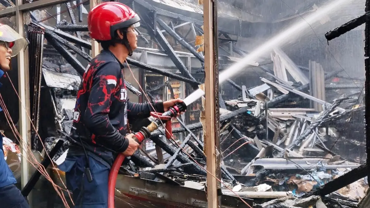 LUDES: Petugas Damkar terus membasahi gerai minimarket yang terbakar.
