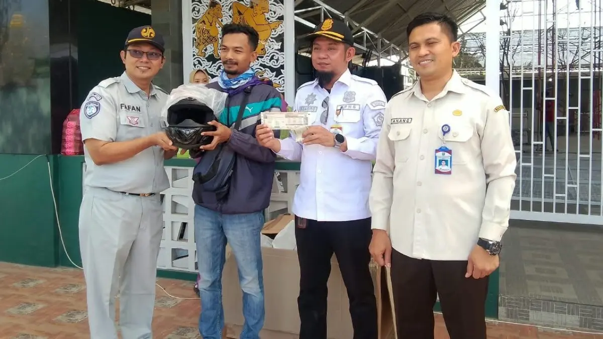 REWARD: BPPD Sidoarjo bersama petugas gabungan saat menyerahkan helm kepada pengendara motor usai membayar pajak di tempat. (DIKY SANSIRI/RADAR SIDOARJO)