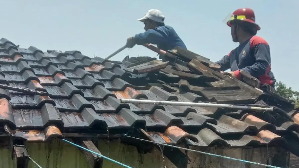 NAIK ATAP: Petugas melakukan pembasahan rumah yang terbakar.