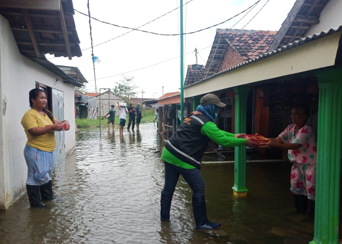 BERBAGI: Relawan BPBD membagikan nasi bungkus pada warga terdampak banjir di Kedungbanteng, Tanggulangin. (RIZKY PUTRI PRATIMI / RADAR SIDOARJO)
