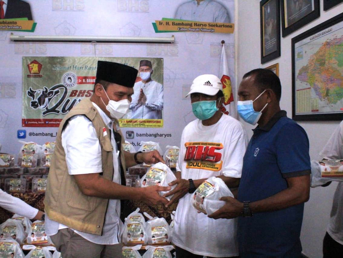MEMBANTU: Ketua Harian Masyarakat Transportasi Indonesia (MTI) Jawa Timur, Bambang Haryo Soekartono (kiri) saat membagikan daging kurban. (HENDRIK MUCHLISON/RADAR SIDOARJO)