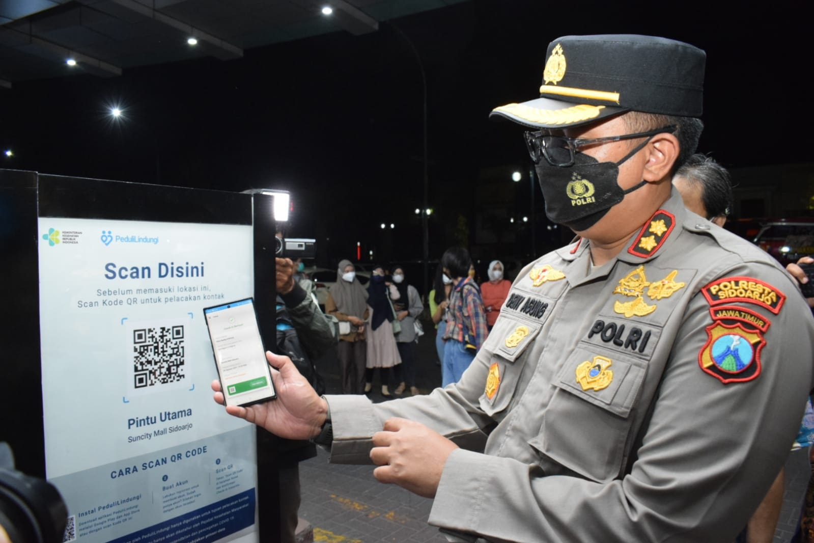 SKRINING: Wakapolresta Sidoarjo AKBP Deny Agung Andriana menunjukkan penerapan scan barcode di aplikasi Peduli Lindungi.
