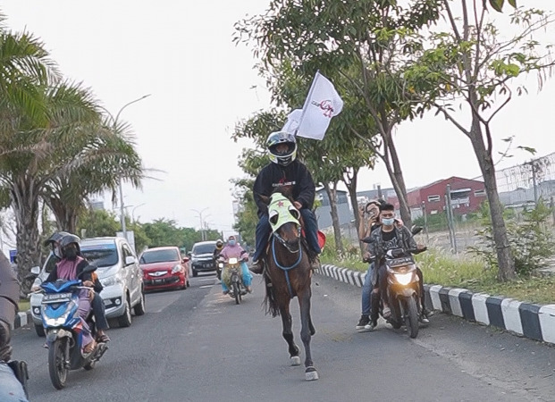 UNIK: Salah satu anggota grup band Castle Angelo naik kuda dengan pakai helm.