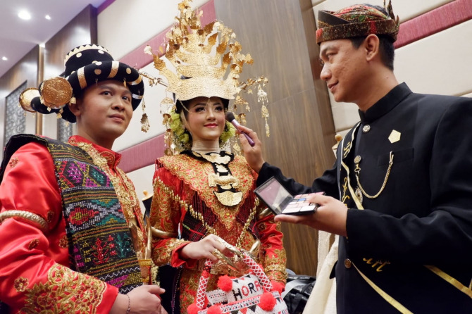 ELEGAN: Egar Siregar (kanan) merapikan riasan wajah model yang menggunakan busana Batak Mandailing Muslim. (RIZKY PUTRI PRATIMI/RADAR SIDOARJO)