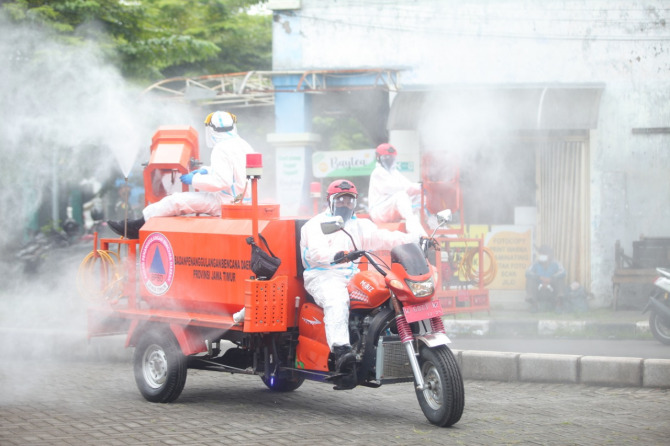 ANTISIPASI : Petugas menyemprot desinfektan di area pasar dan Terminal Larangan. (HENDRIK MUCHLISON/RADAR SIDOARJO)
