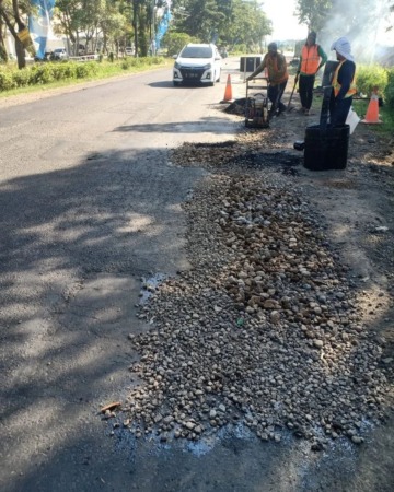 SEGERA LAPOR: Tim satgas jalan Dinas PUBMSDA saat melakukan penambalan Jalan Lingkar Timur. (RIZKY PUTRI PRATIMI/RADAR SIDOARJO)