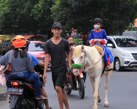SANTAI: Salah satu anak menunggang kuda di Jalan Gading Fajar. (HENDRIK MUCHLISON/RADAR SIDOARJO)