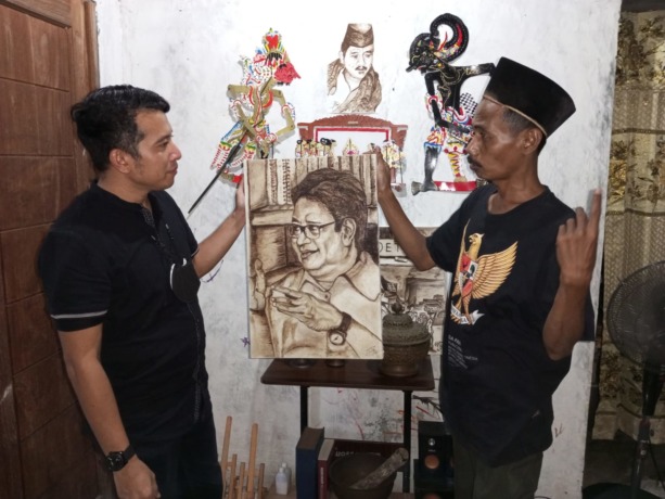 SEMPAT MIMPI: Ketua DPD Partai Golkar Sidoarjo, Adam Rusydi (kiri) melihat hasil lukisan Airlangga Hartarto dari cethe kopi oleh seniman Sidoarjo.