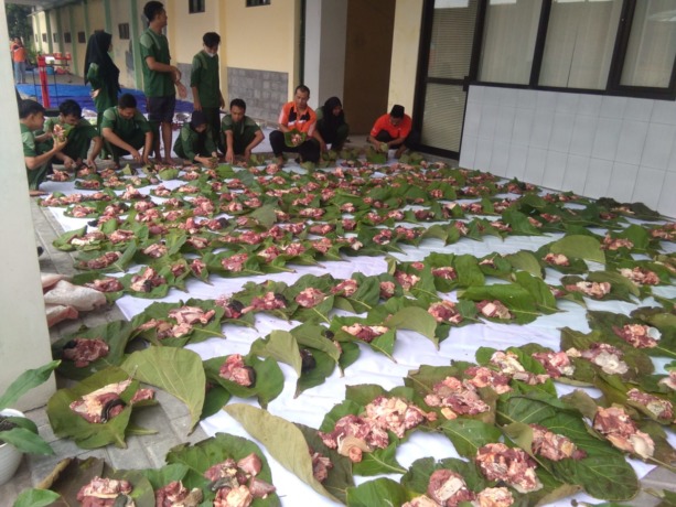 MASIH SEGAR: Ratusan daging kurban dibungkus dengan daun jati sebelum dibagikan ke masyarakat. (ANAS/RADAR SIDOARJO)