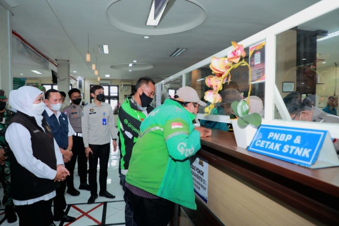 MERINGANKAN: Gubernur Jatim Khofifah Indar Parawansa saat melihat proses pembayaran pajak kendaraan bermotor yang digratiskan. (HENDRIK MUCHLISON/RADAR SIDOARJO)