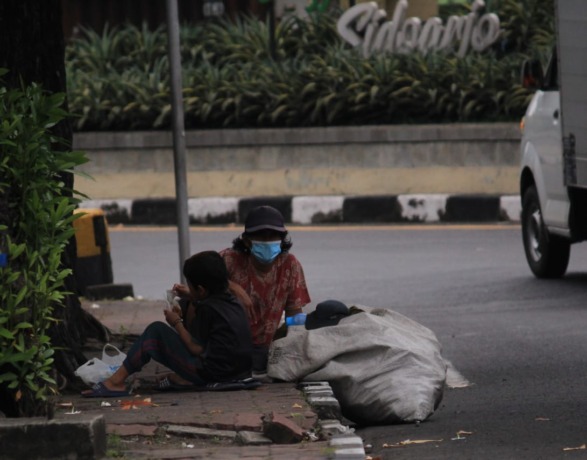 SULIT DITERTIBKAN: Pengemis di salah satu jalan protokol di Sidoarjo membawa anaknya. (HENDRIK MUCHLISON/RADAR SIDOARJO)