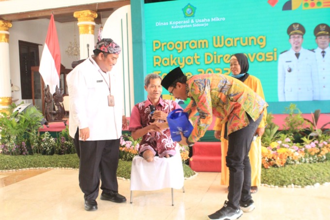 SENANG: Bupati Sidoarjo Ahmad Muhdlor menerima souvenir dari salah satu warga yang warungnya direnovasi. (HENDRIK MUCHLISON/RADAR SIDOARJO)