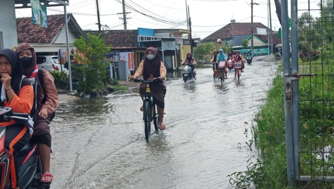 SEMANGAT: Sejumlah siswa di Tanggulangin saat pulang sekolah dengan mengenakan sandal akibat genangan yang tak kunjung surut. (LUKMAN ALFARISI/RADAR SIDOARJO)