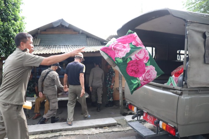RAZIA: Petugas Satpol PP Sidoarjo saat mengangkut barang-barang yang berada di dalam bangunan. (LUKMAN AL FARISI/RADAR SIDOARJO)
