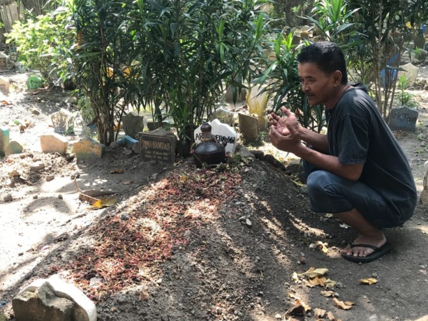 BERDUKA: Mat Sochib paman Arik saat menunjukkan makam keponakannya. (ZAINUL FAJAR/RADAR SIDOARJO)