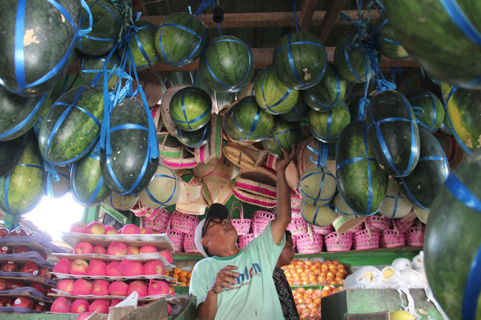 Suwoto salah satu pedagang di Pasar Citra Niaga menata buah segar di lapaknya.
