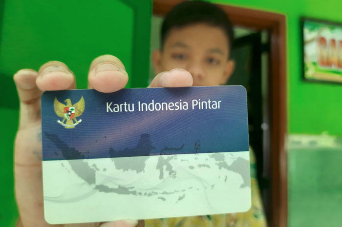 Ilustrasi siswa menunjukkan Kartu Indonesia Pintar (KIP) miliknya