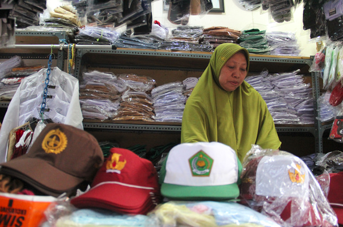 : Nur Khofifah, 58 menata sejumlah atribut dan seragam sekolah siswa di Pasar Senggol Bayangkara Jombang kemarin (13/7).