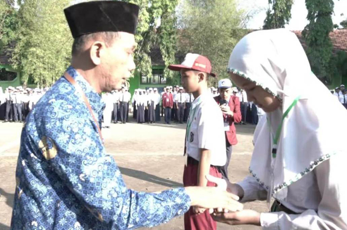 Kepala SMPN 1 Diwek Suprihadiono SPd melakukan pengalungan tanda pengenal kepada peserta MPLS