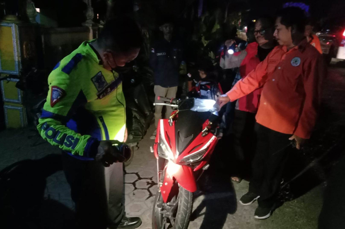 Petugas kepolisian saat mengamankan sepeda motor yang terlibat kecelakaan maut di jalan kabupaten Desa Japanan, Kecamatan Mojowarno