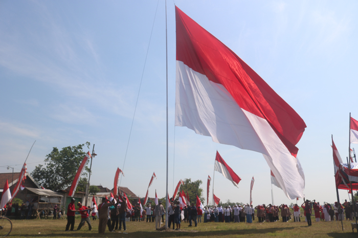 Sejumlah warga di Dusun Canggon, Desa Ngudirejo, Kecamatan Diwek saat gotong-royong mengibarkan bendera raksasa