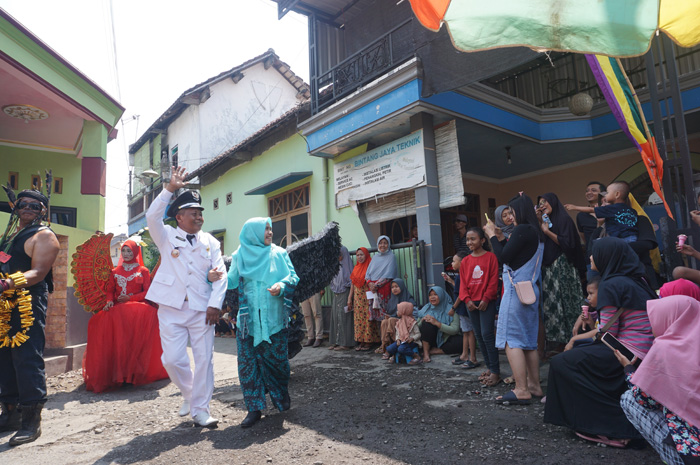 Kepala Desa Gambiran, Jupri beserta istri menyapa warga yang menyaksikan pawai karnaval Desa Gambiran