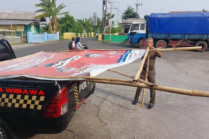 Petugas dari Satpol PP Jombang sedang melakukan Penertiban baliho caleg dengan foto Pj Bupati Jombang di wilayah Bandarkedungmulyo