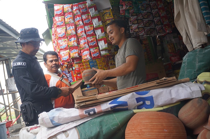 Kades Bandung Anang Fauzi (kiri) bersama perangkat desa menunjukkan barang dagangan milik salah satu pedagang pasar desa, Jumat (1/12).