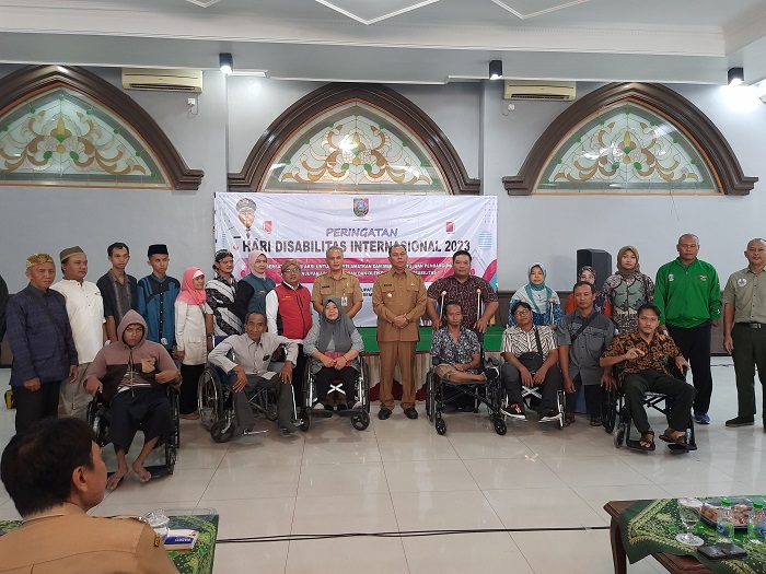 Pj Bupati Sugiat, didampingi Hari Purnomo dan M Saleh menyampaikan bantuan secara simbolis kepada perwakilan penyandang disabilitas, di Islamic Center Jombang, Selasa (5/12).