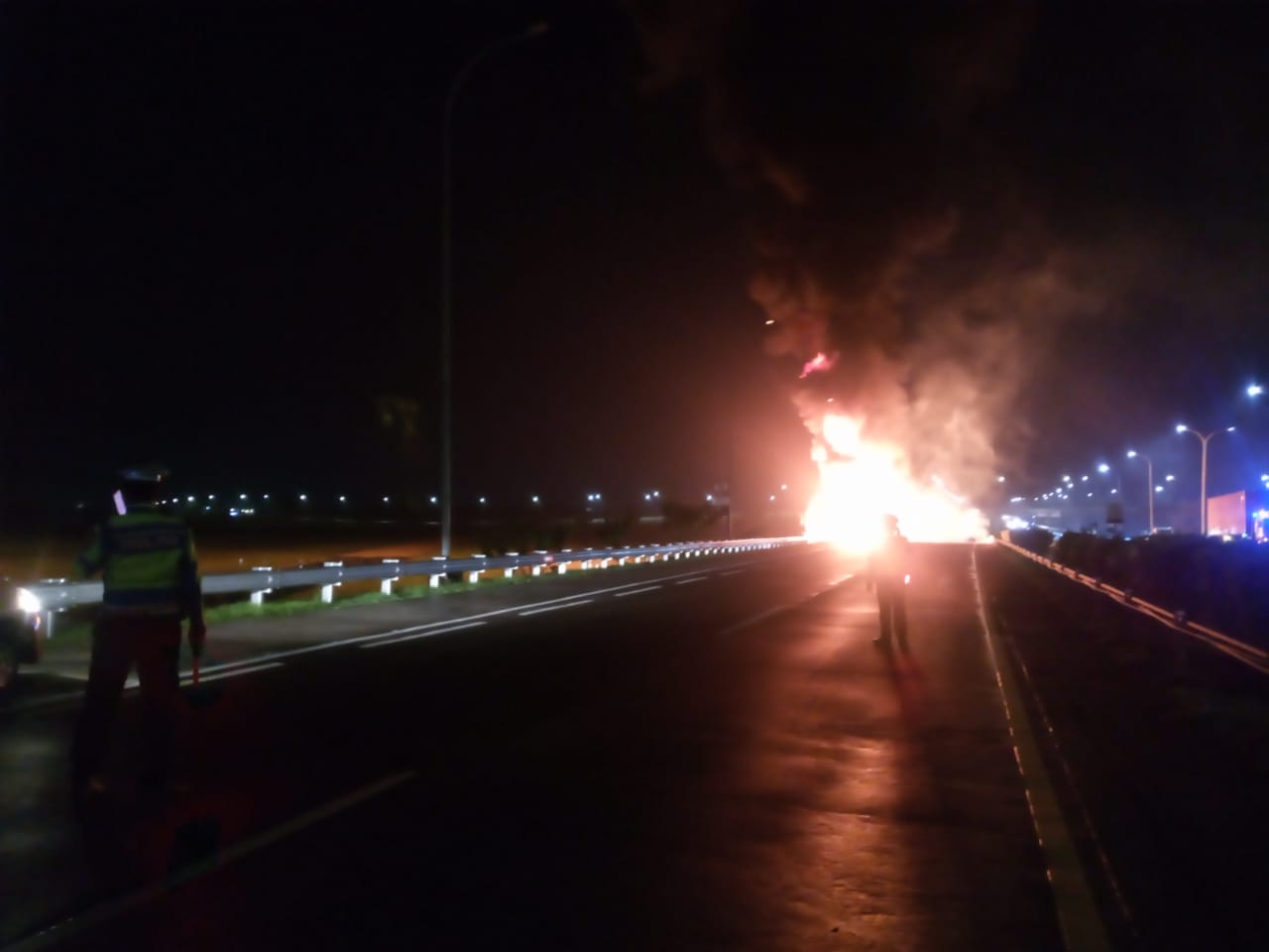 Petugas kepolisian berjaga saat proses pemadaman api yang melanda truk tangki di Tol Jombang-Mojokerto dilakukan.