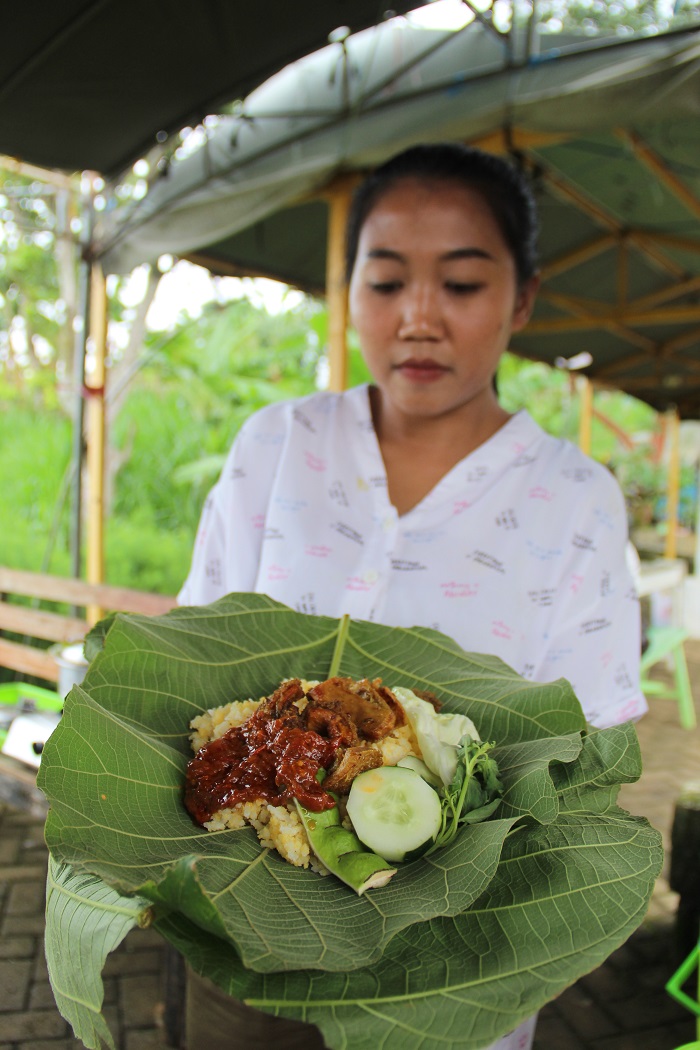 Alina Dini, penjual nasi babat daun jati di Dusun Pucangrejo, Desa/Kecamatan Wonosalam, menujukkan nasi babat bungkus daun jati di warungnya, Rabu (13/12).