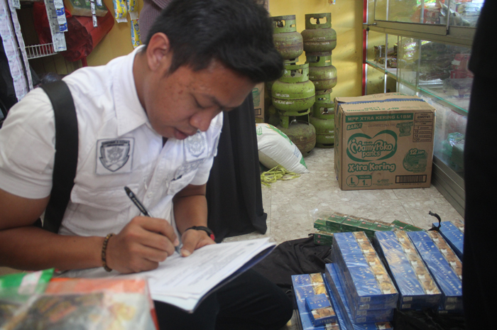 Petugas mendata sejumlah rokok ilegal yang ditemukan di toko kelontong saat razia gabungan